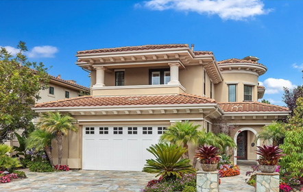 Mediterranean-style two-story house with beige stucco walls and terracotta tiles, featuring a white double garage door and detailed landscaping, ready for home inspection on a partly cloudy day.